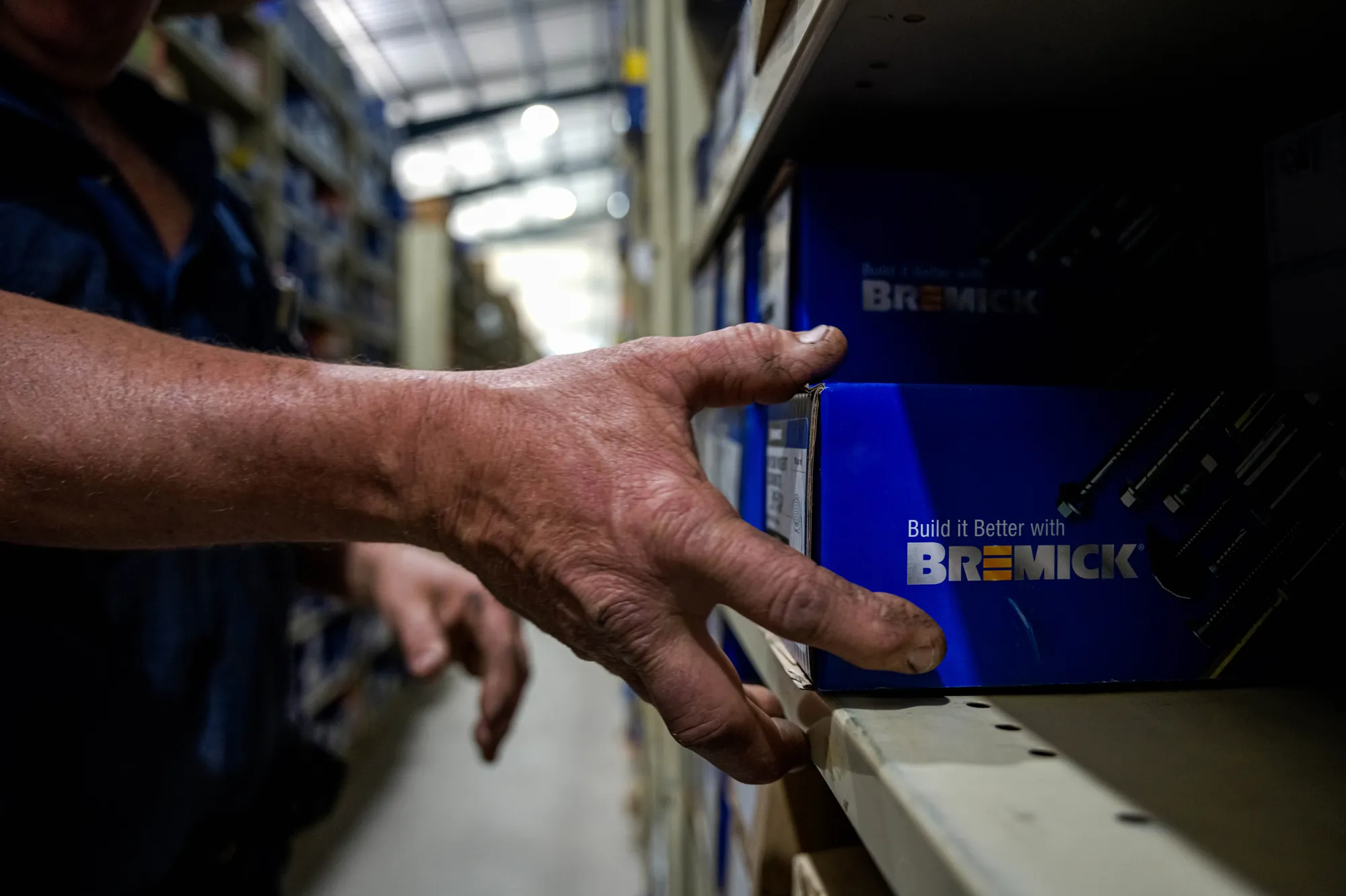 Hand reaching for a box of Bremick fasteners on the shelf