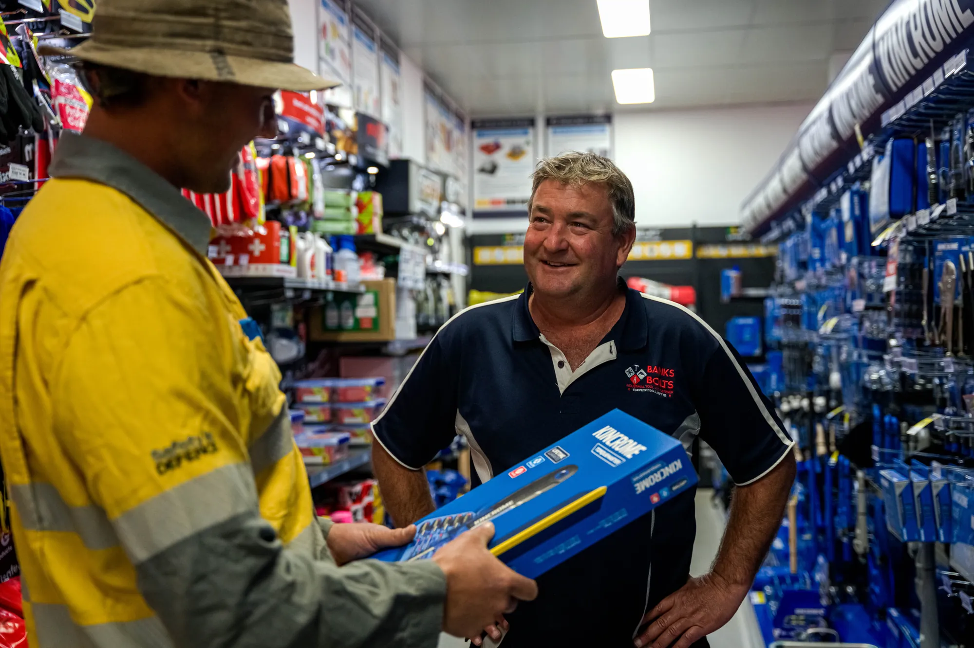 Staff member handing a boxed power tool to a customer in the store