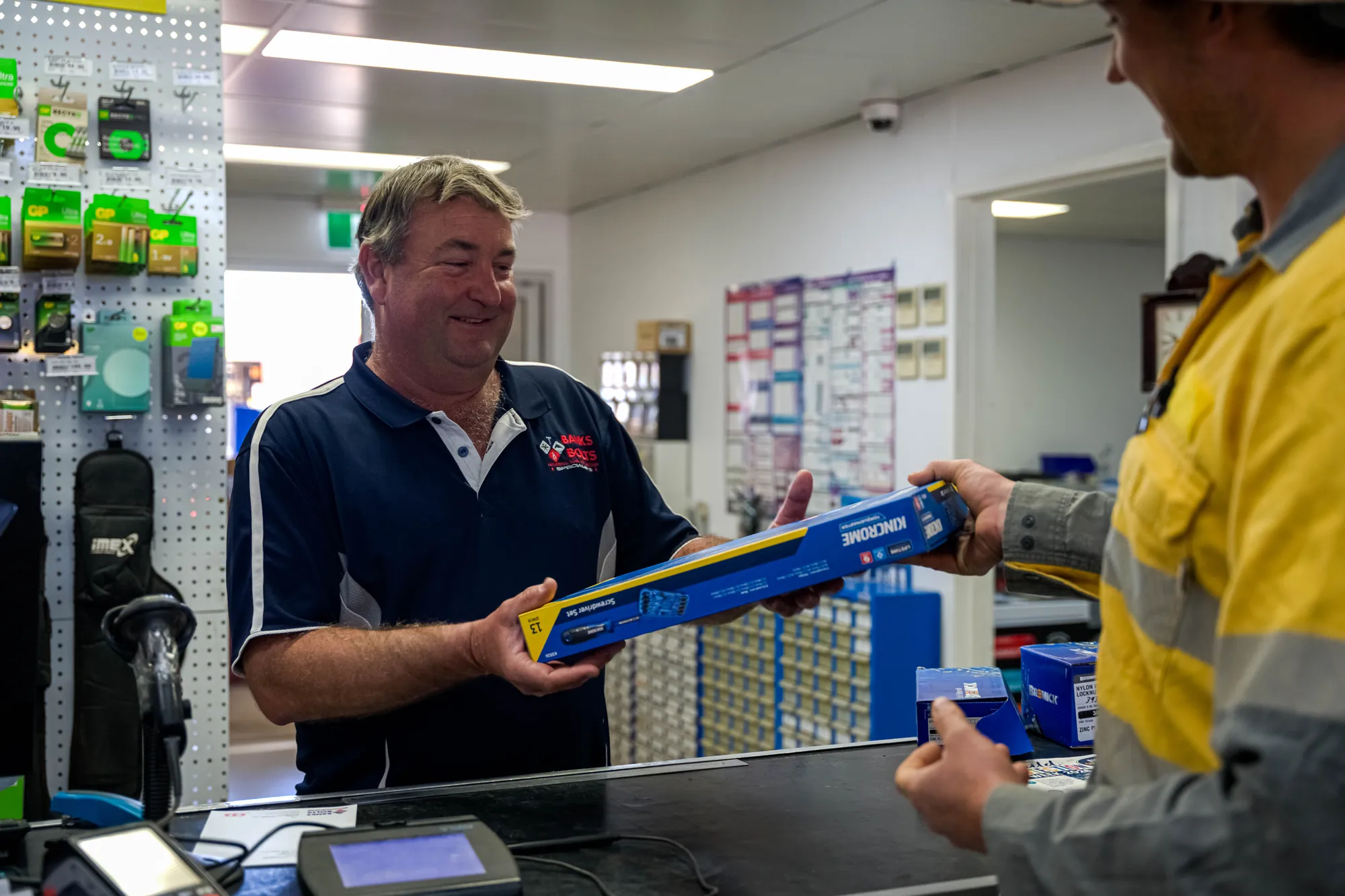 Staff member serving a tradie at the front counter in Roma