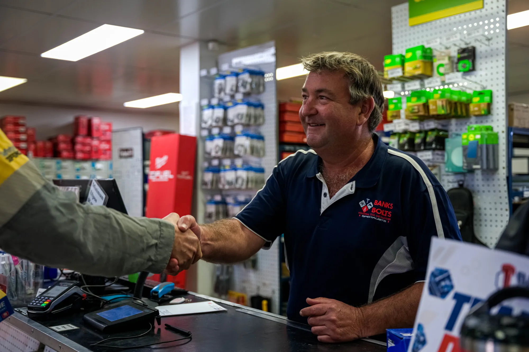 Staff member shaking hands with a customer at the counter