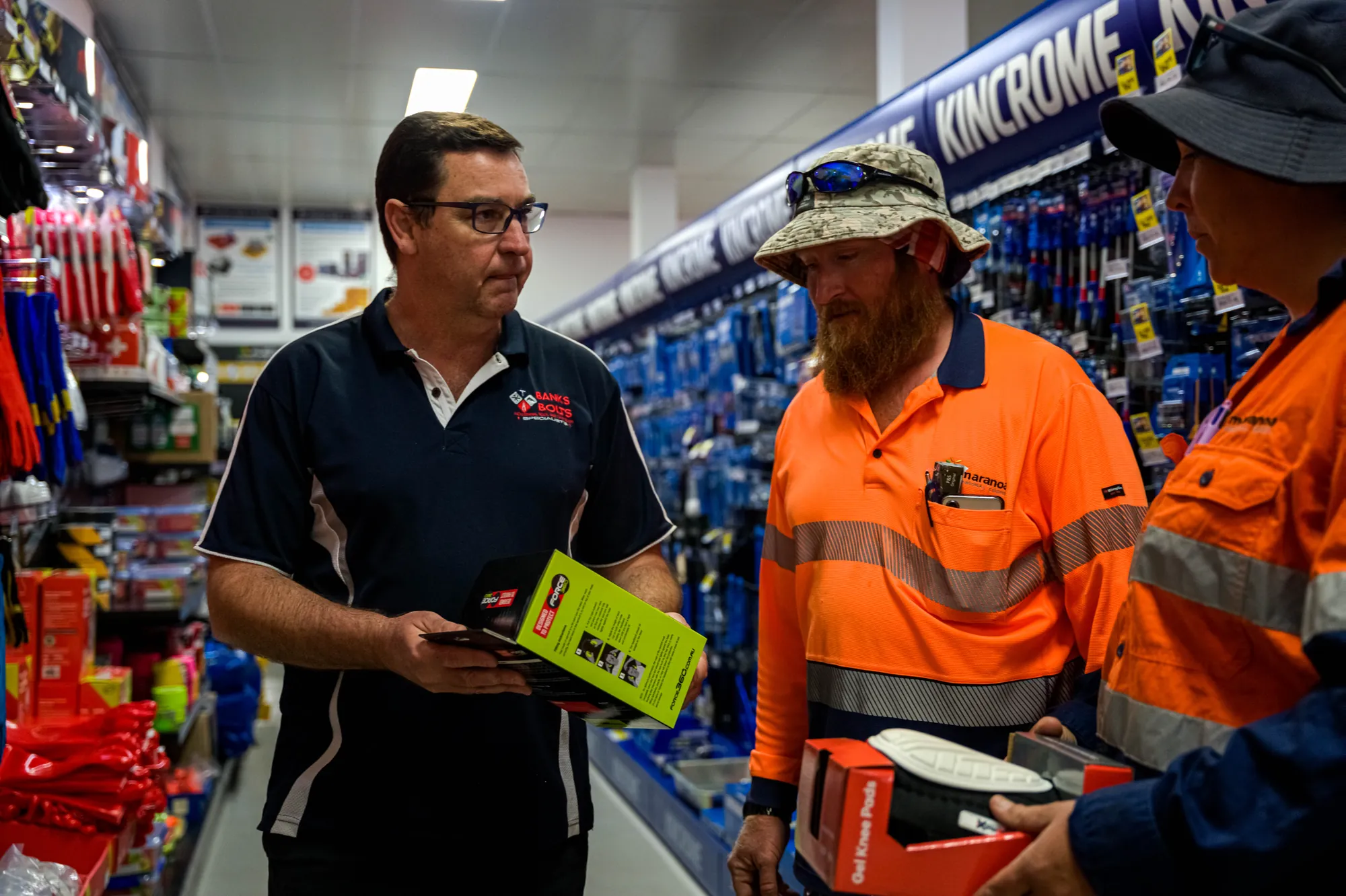 Staff member showing a product to tradies in the Kincrome aisle